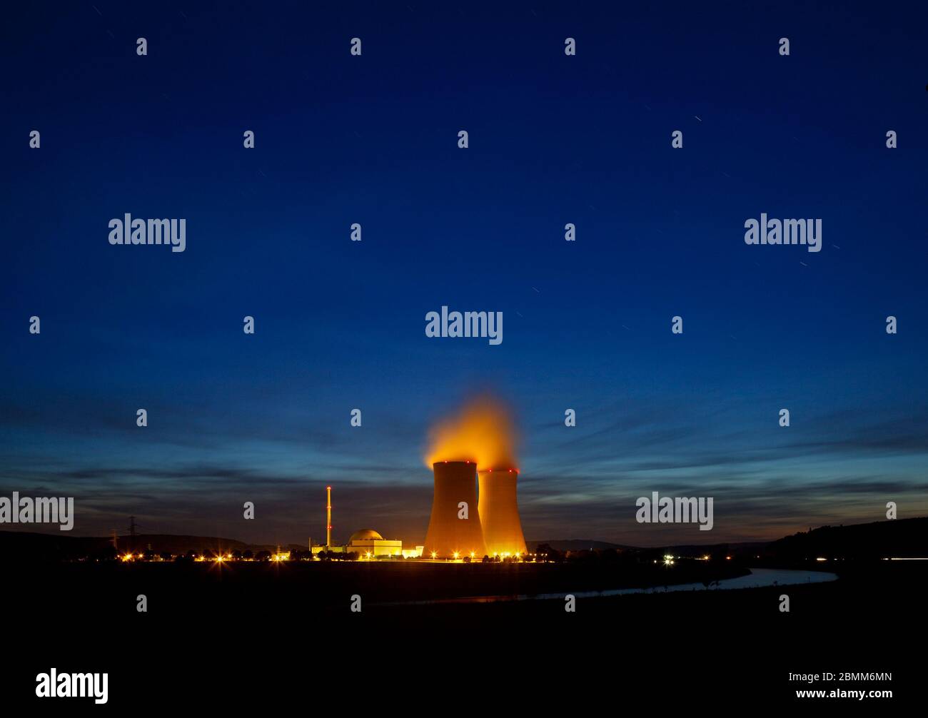 Nachtaufnahme eines Kernkraftwerks in der Nähe eines Flusses mit blauem Nachthimmel. Stockfoto