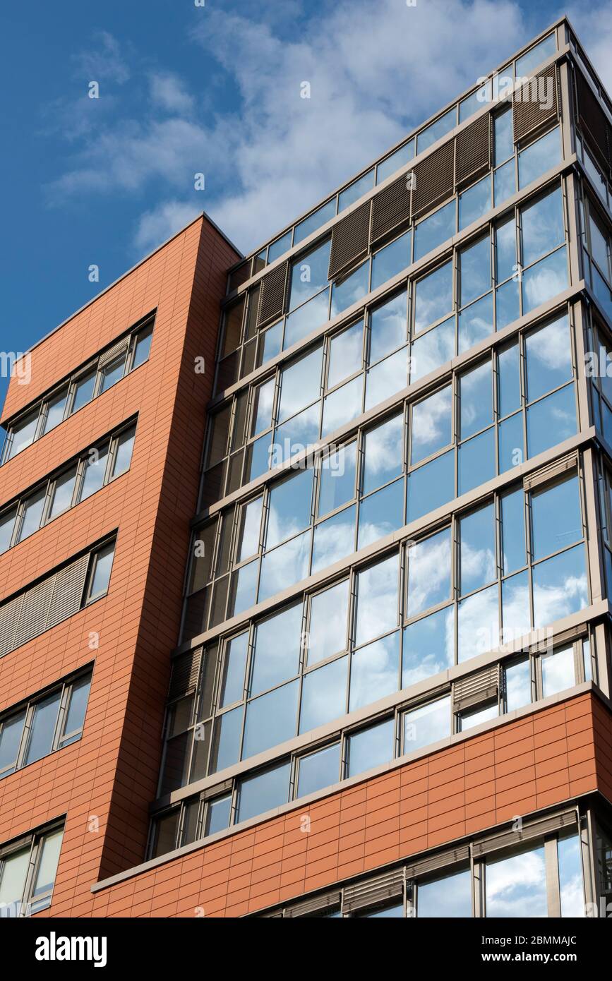 Fassade aus Büroglas und Reflexionen von unten vor blauem Himmel Stockfoto