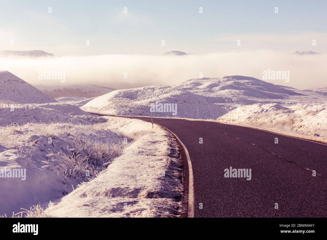 Biegen Sie in einer leeren Straße nach Glencoe in Richtung Berge und einer Bank von eisigen Nebel an einem sonnigen Wintertag in Schottland Stockfoto