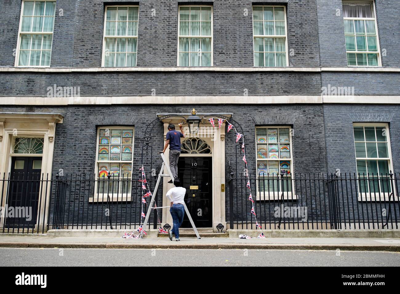 Downing Street Mitarbeiter entfernen Union Flagge Bunting von der Front der Nr. 10 Downing Street nach VE Tag, vor Premierminister Boris Johnson Rede an die Nation später am Abend. Stockfoto