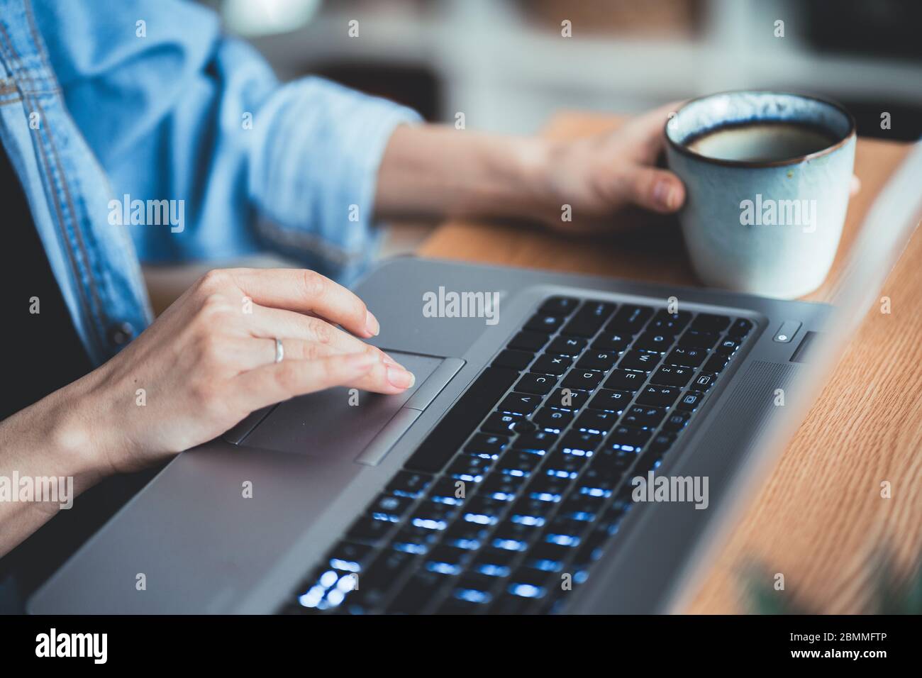 Nahaufnahme Hand des Mädchens hält Kaffeebecher. Business Frauen Eingabe und Scrollen Tastatur auf Laptop. Technologie Frau Konzept aus dem Büro Stockfoto