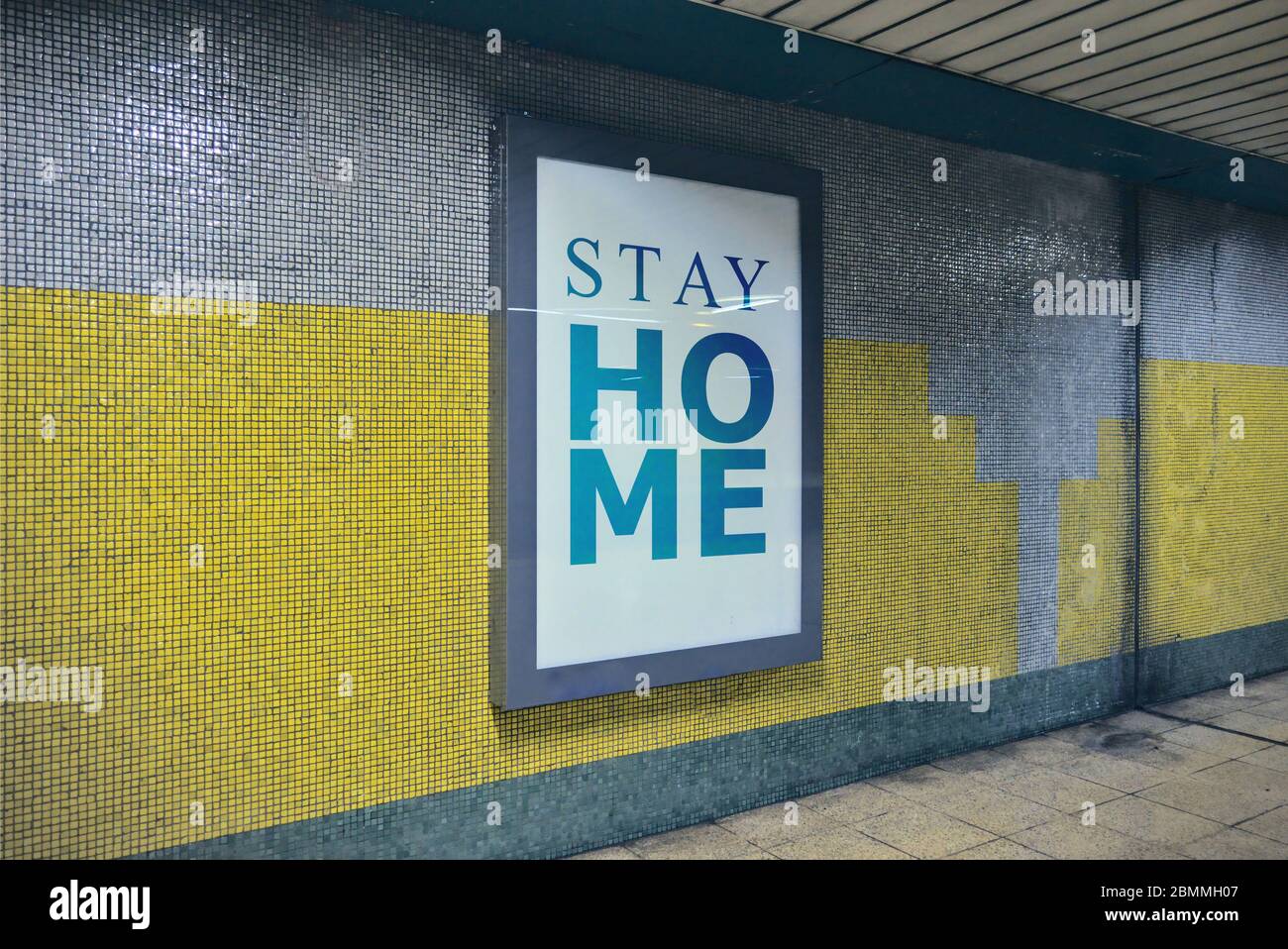 Bewusstsein Anhebung Plakatwand mit der Botschaft von zu Hause bleiben Anfrage, um die Menschen sicher bleiben von Coronavirus an einer Wand an U-Bahn-Korridoren platziert Stockfoto