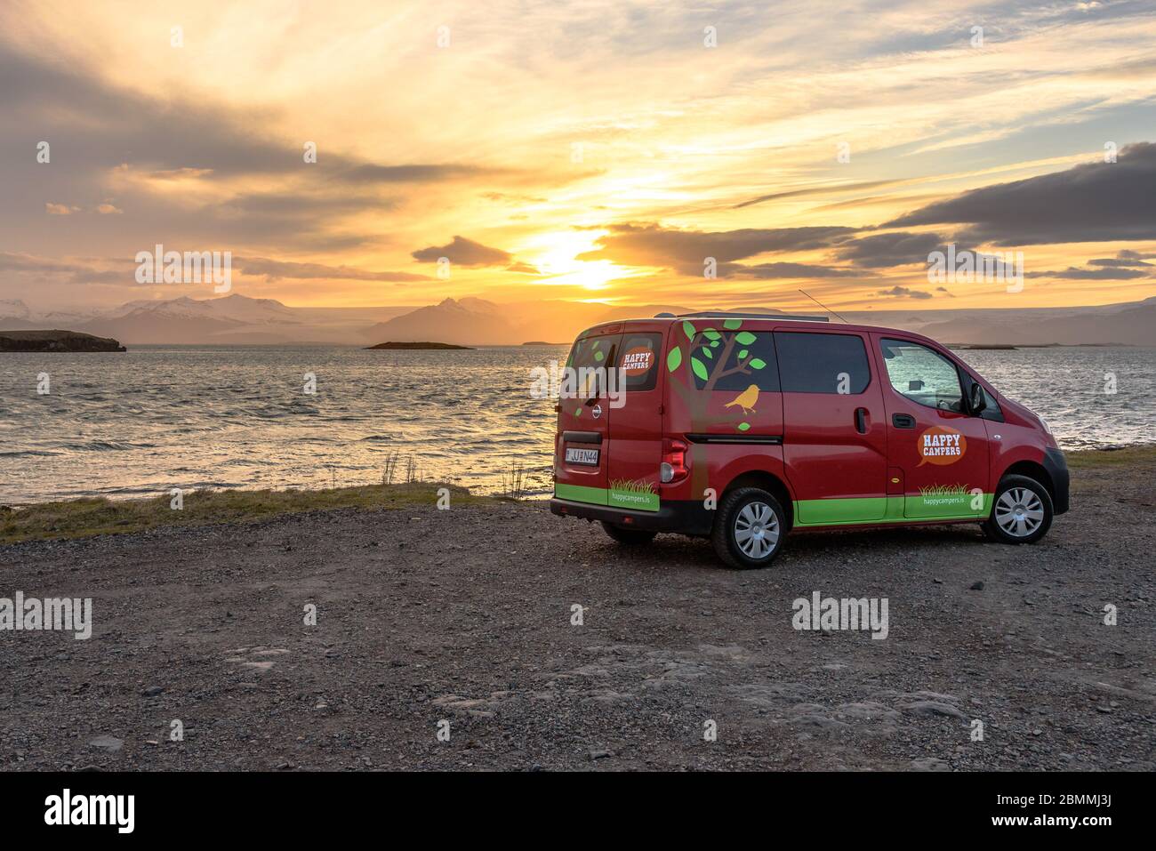 Ein Happy Camper Camper, der bei Sonnenuntergang am Wasser in Osland südlich von Hofn, Island, geparkt hat Stockfoto