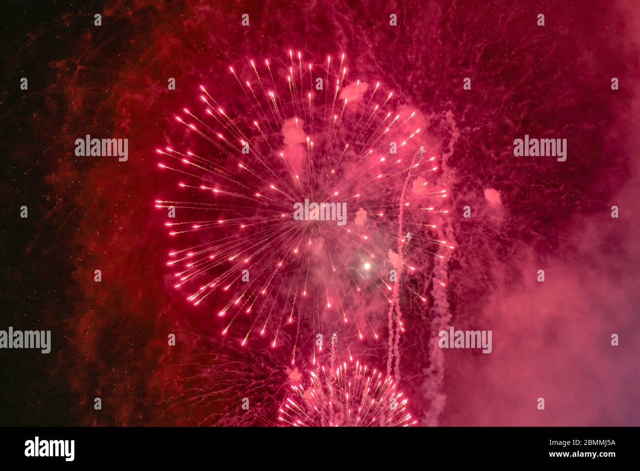Rotes Feuerwerk mit Rauch über dem schwarzen Himmel. Geringe Tastenbelichtung. Stockfoto