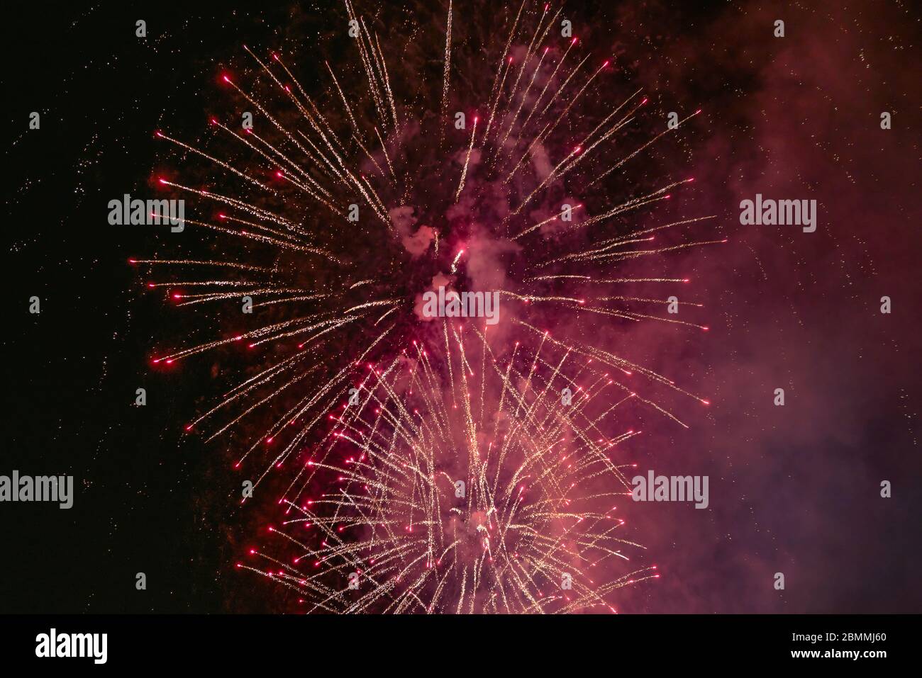 Rotes Feuerwerk mit Rauch über dem schwarzen Himmel. Geringe Tastenbelichtung. Stockfoto