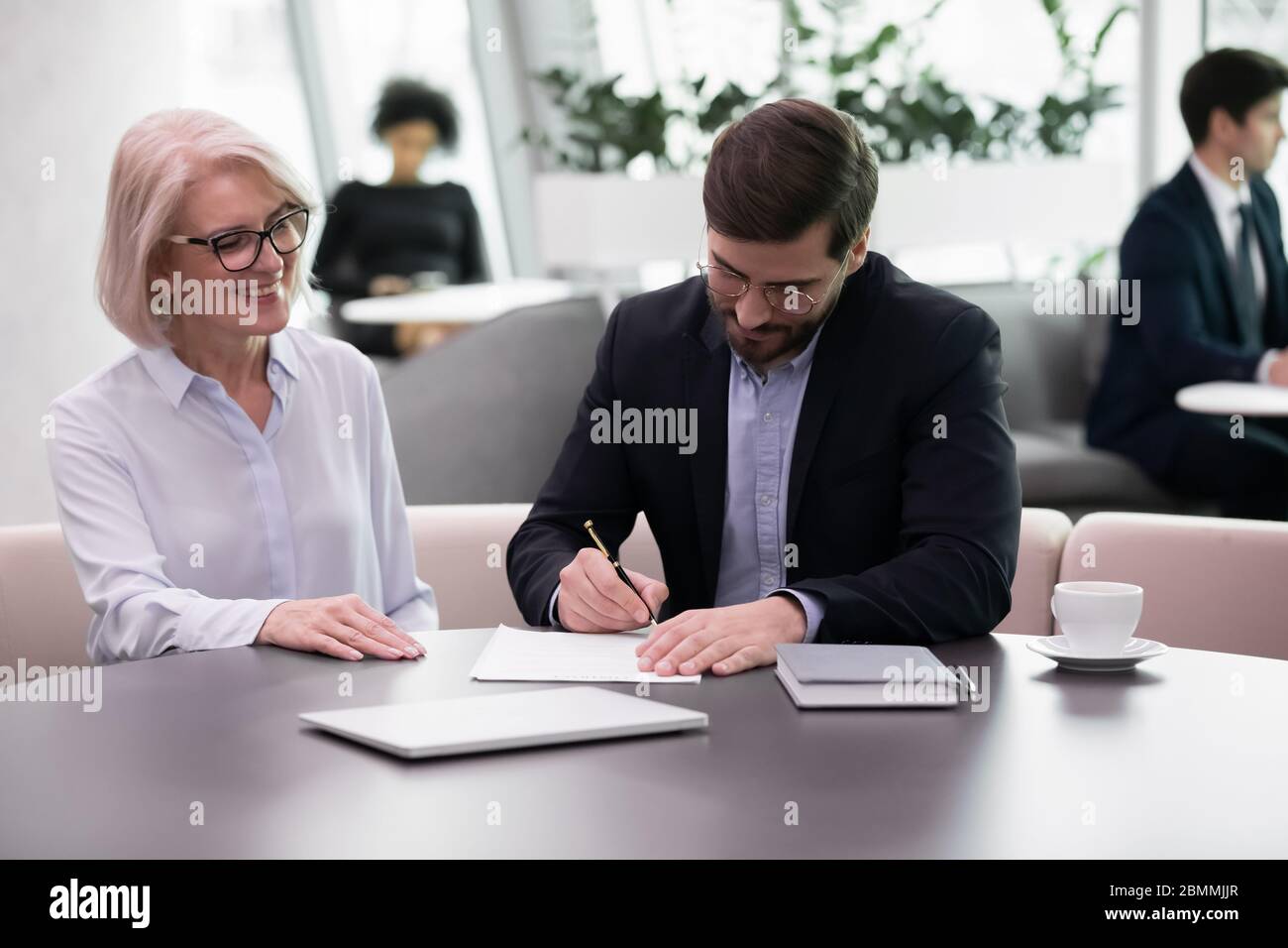 Reife Millennial Partner unterzeichnen Vertrag, der während des Meetings finanzielle Vereinbarung macht Stockfoto