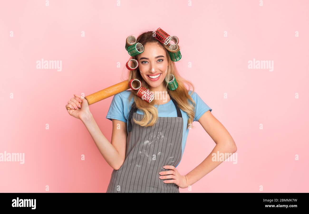 Happy girl mit Nudelholz auf der Schulter und Schürze mit Mehl verschmiert Stockfoto