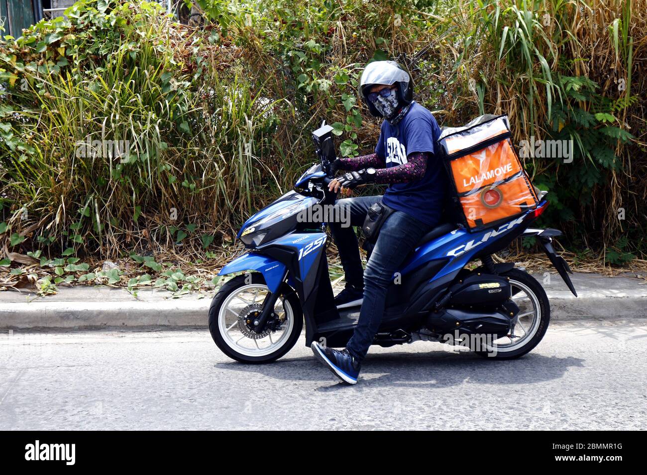 Antipolo City, Philippinen - 7. Mai 2020: Lieferung auf Anfrage Motorrad Kurier mit einem Paket zur Lieferung. Stockfoto
