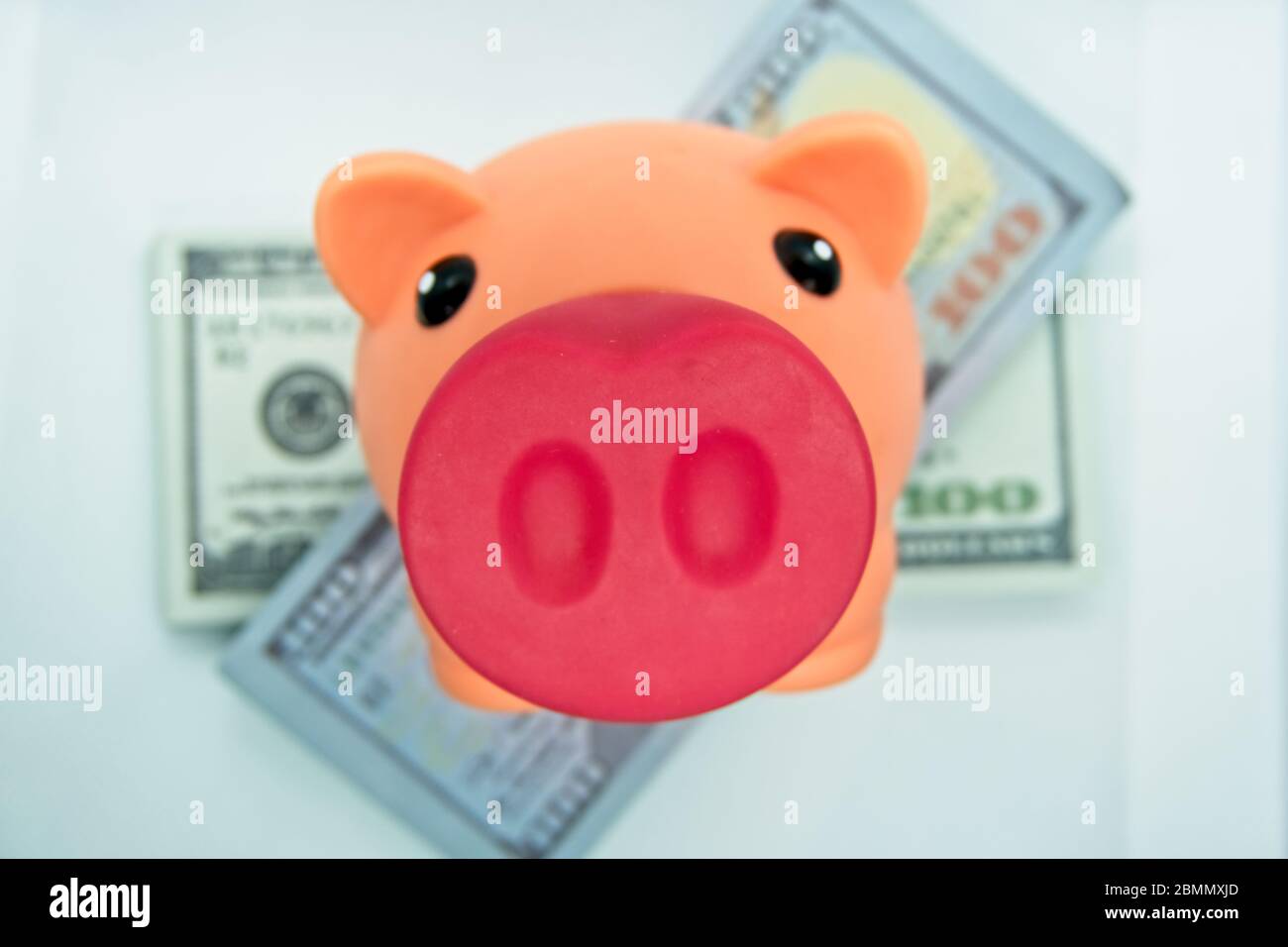 Sparschwein auf einem Wad von hundert Dollar-Scheinen in einem weißen Hintergrund Stockfoto