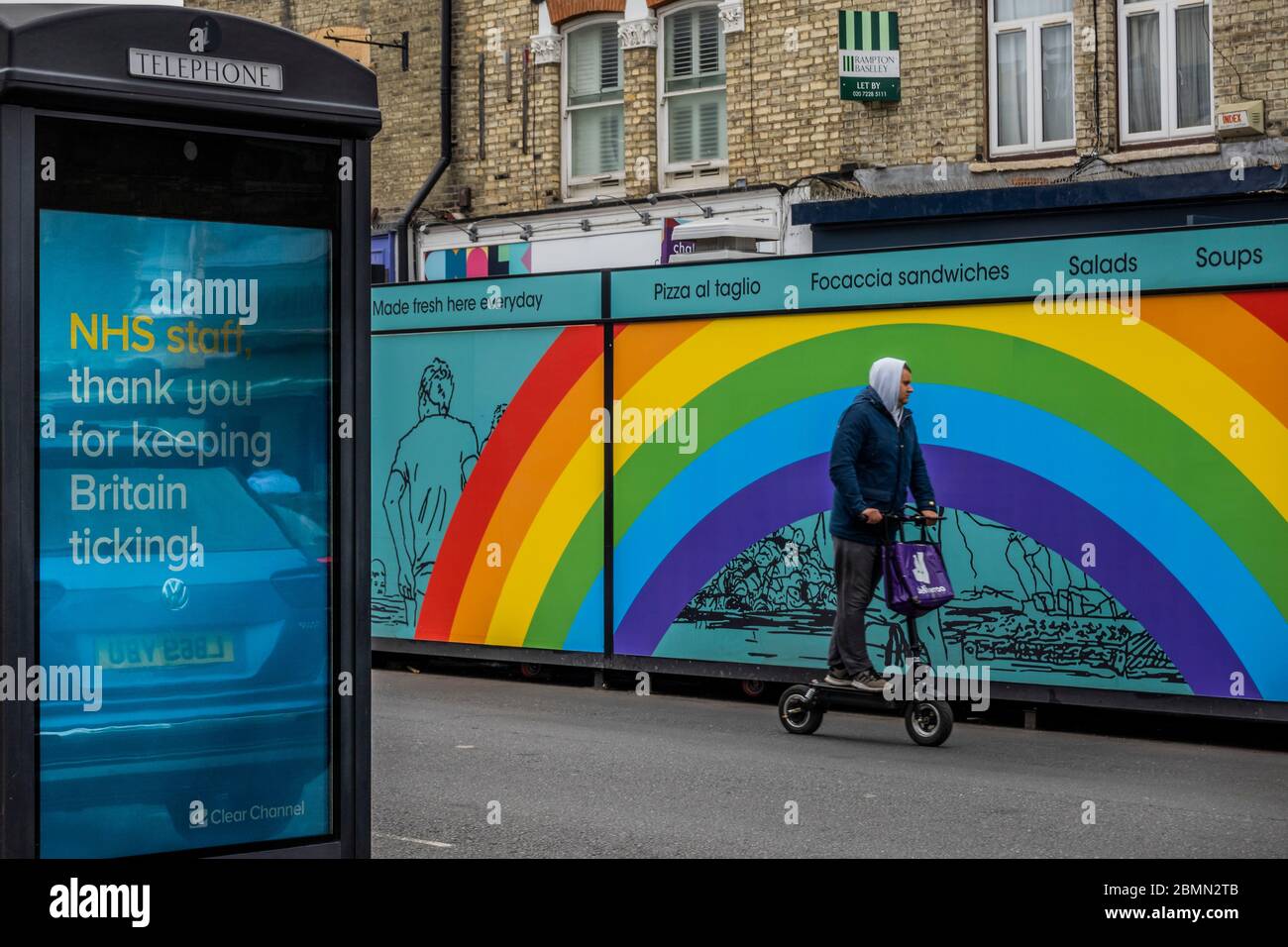 London, Großbritannien. Mai 2020. Ein deliveroo Fahrer auf einem Elektroroller fährt vorbei an Rainbow und anderen Nachrichten der Unterstützung für die NHS. Der Tag der großen Ankündigung der Regierungen über die mögliche Lockerung der Beschränkungen. Die "Lockdown" geht weiter für den Ausbruch des Coronavirus (Covid 19) in London. Kredit: Guy Bell/Alamy Live News Stockfoto