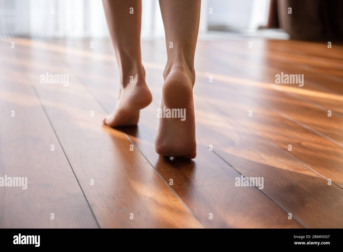 Frau, die barfuß auf den Zehen läuft, bei einem Blick auf die Nahaufnahme des warmen Bodens Stockfoto