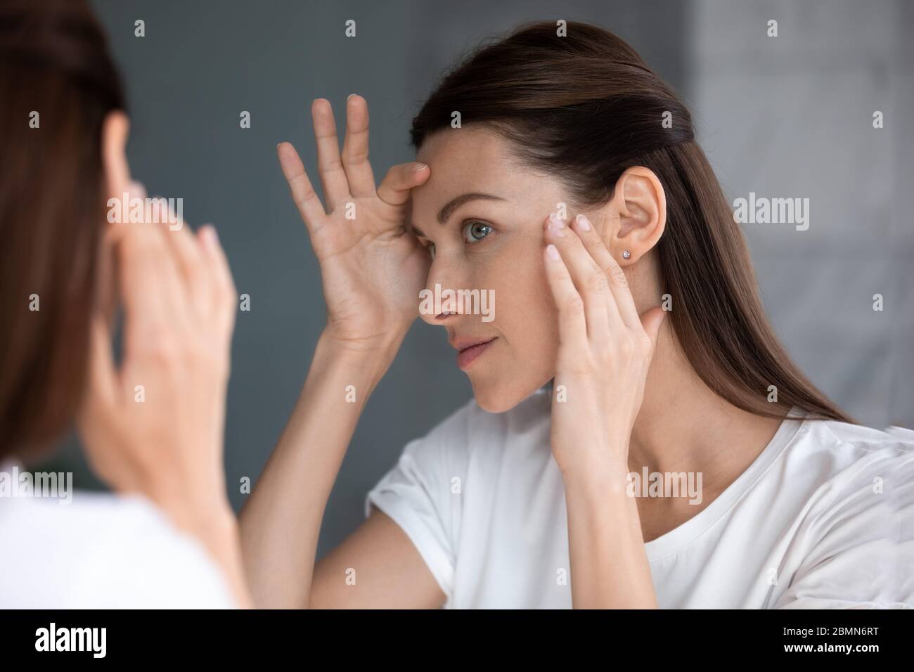 Zufriedene Frau suchen in Spiegel Check Gesicht nach Schönheitsbehandlung Stockfoto