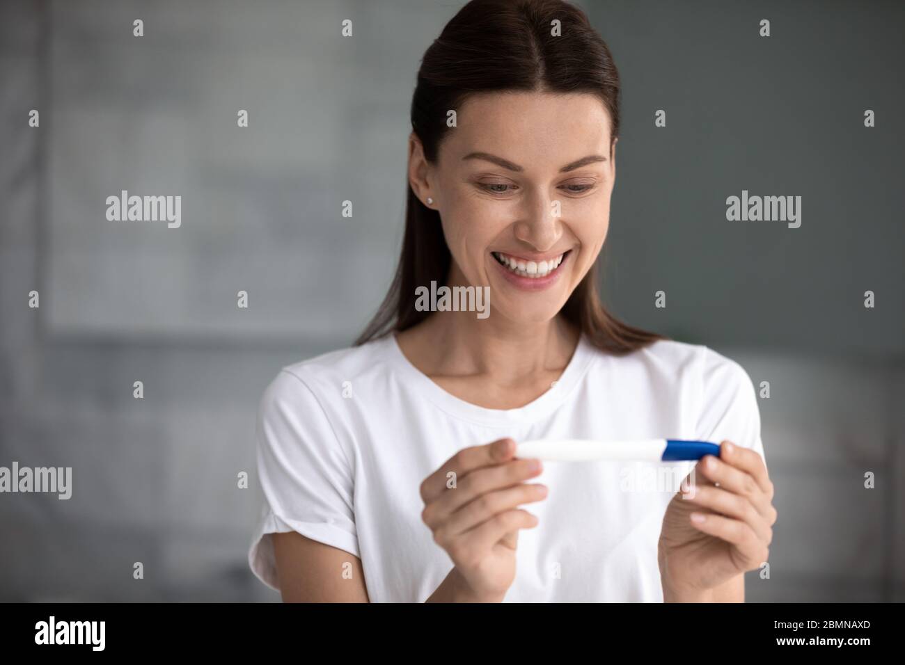 35s Frau hält Schwangerschaftstest sah zwei Streifen fühlt sich glücklich Stockfoto