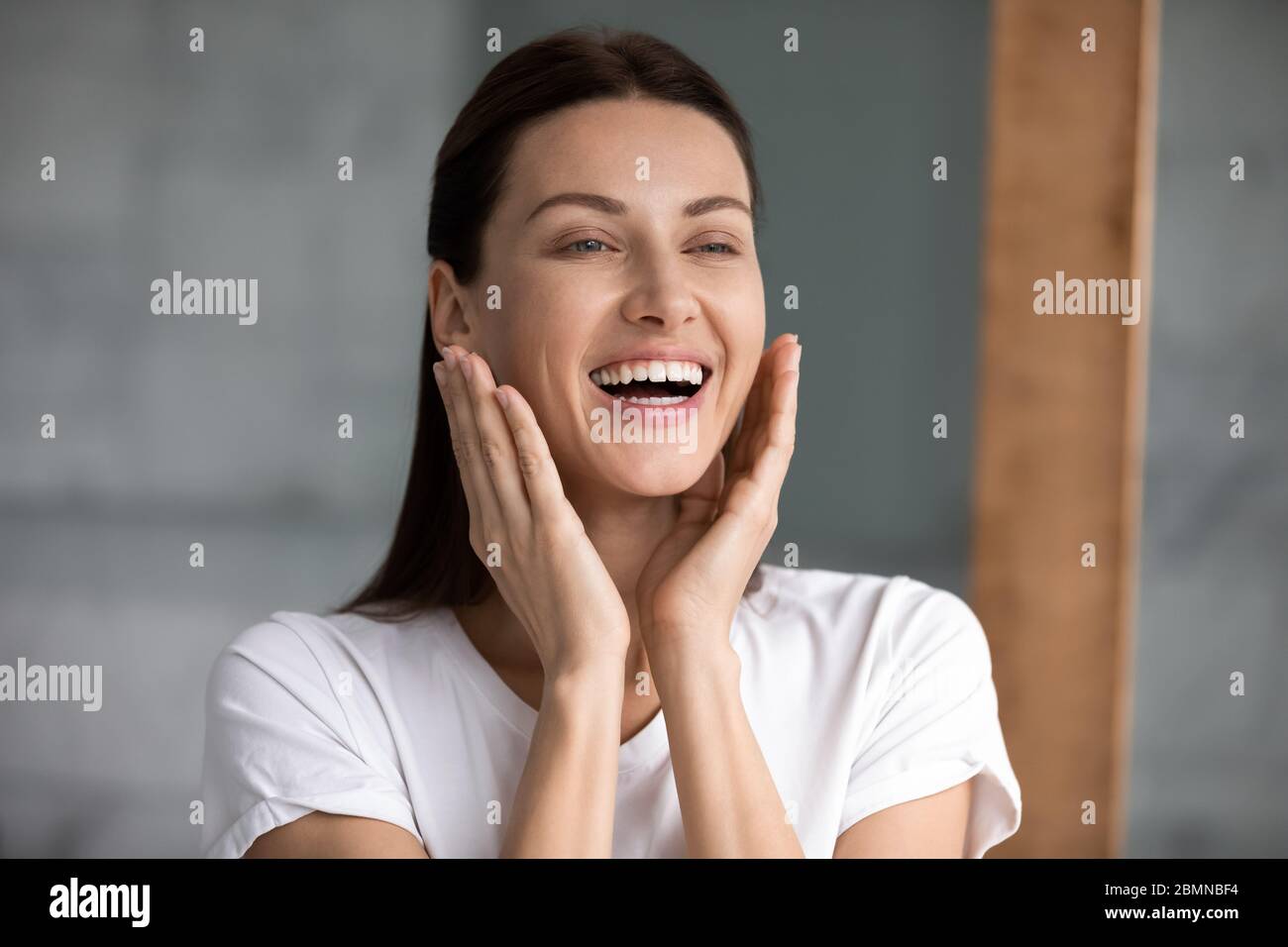 Schöne Frau berühren Gesicht genießt perfekte Haut nach feuchtigkeitsspendende Creme Stockfoto