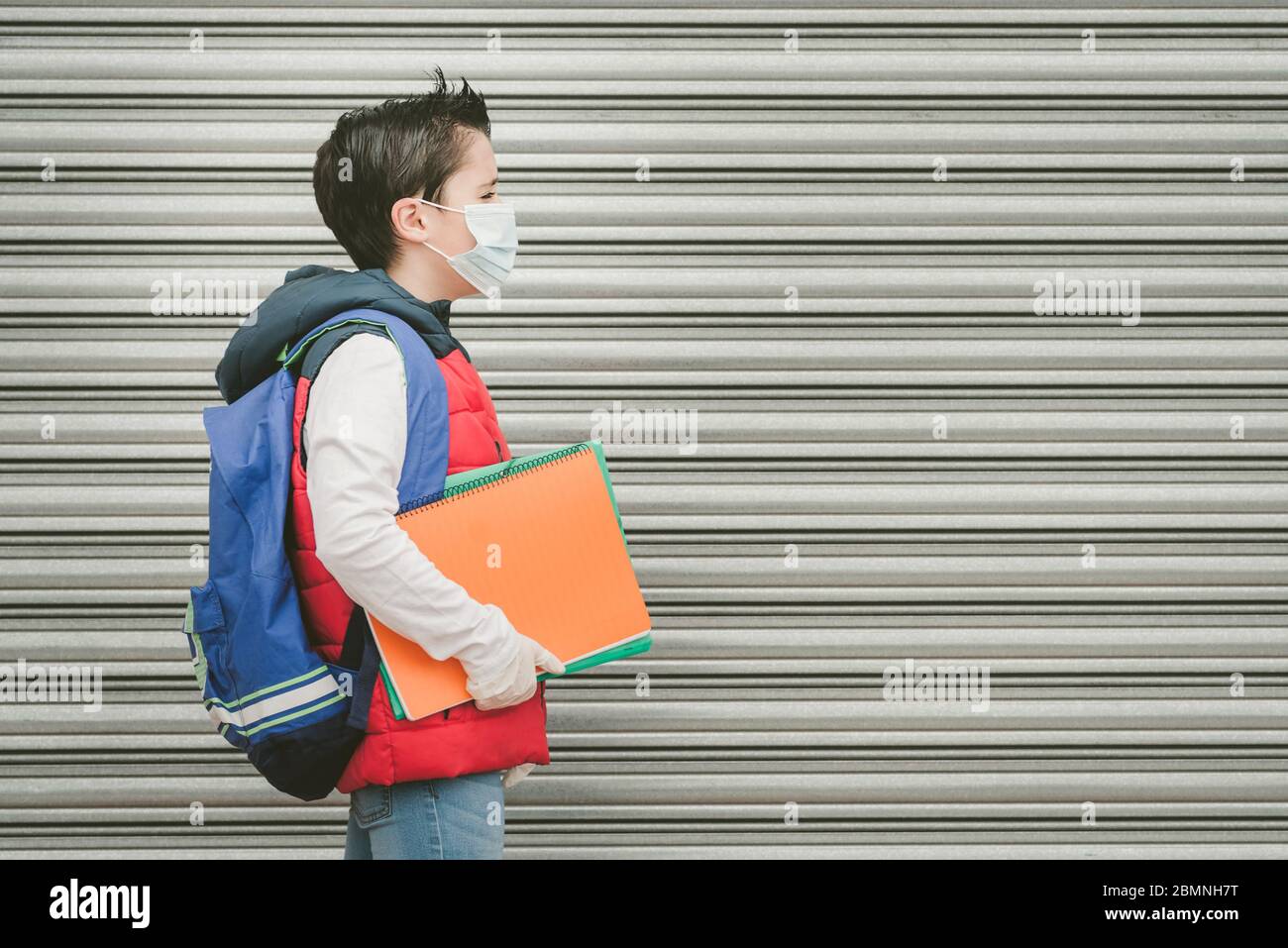 Covid-19, Kind mit medizinischen Maske und Rucksack, der zur Schule geht im Freien Stockfoto