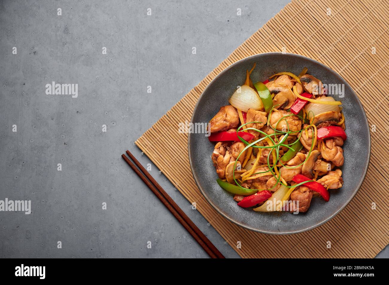 Thai Ginger Chicken oder Gai Pad King in grauer matter Schale auf Betonhintergrund. Gai Pad King ist Thailand Küche Gericht mit Hühnerfleisch, Ingwer Streifen, o Stockfoto