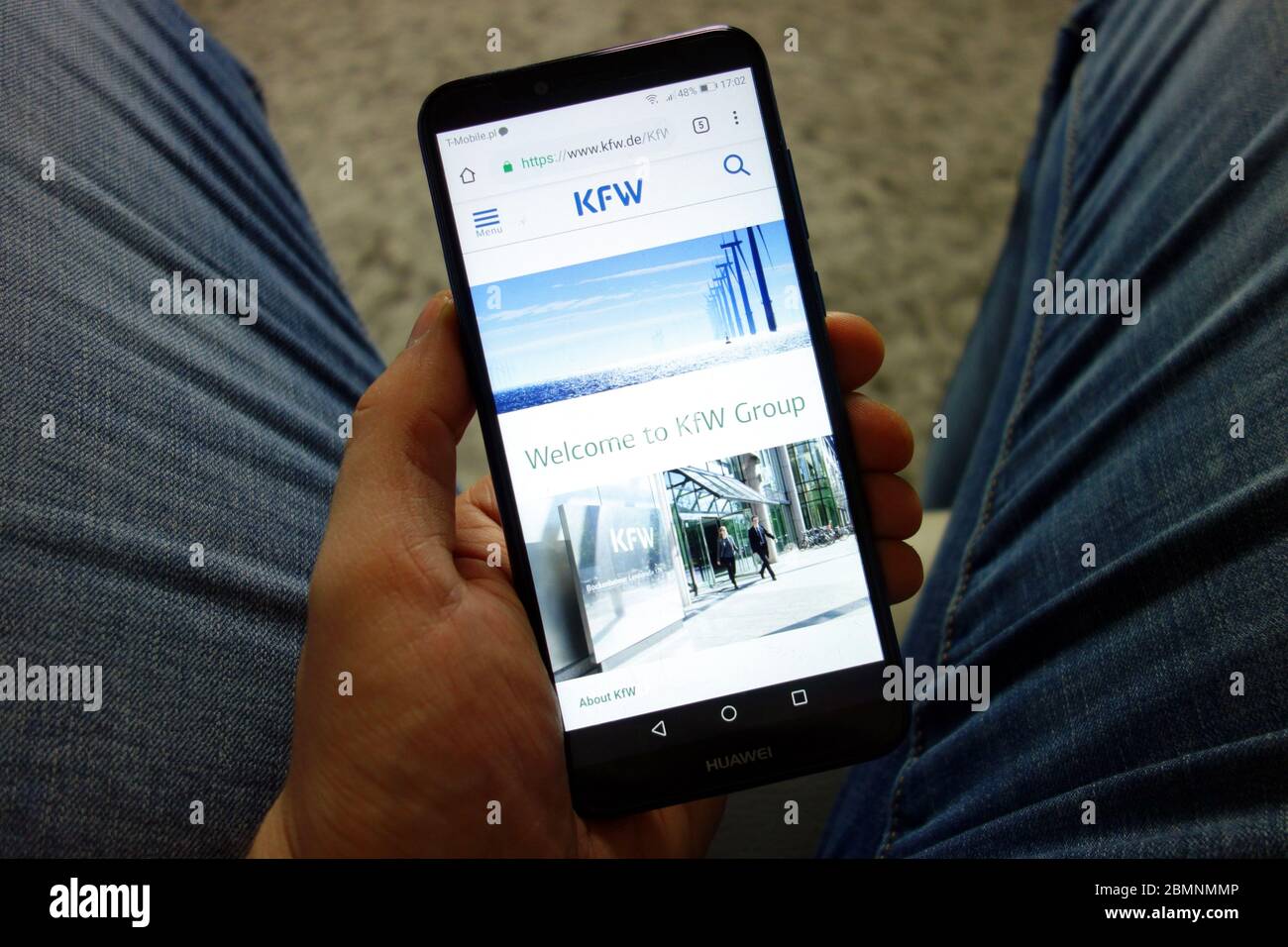 Mann hält Huawei Smartphone mit KfW Bank Website angezeigt. Konzept des Online-Banking Stockfoto