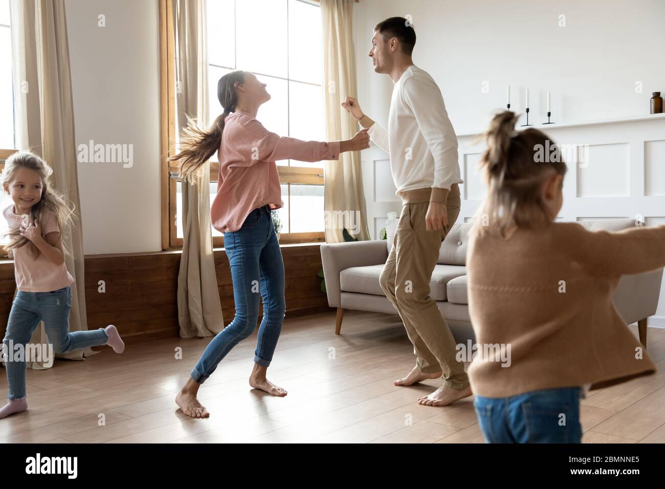 Glückliche Familie mit zwei Töchtern, die im Wohnzimmer tanzen Stockfoto