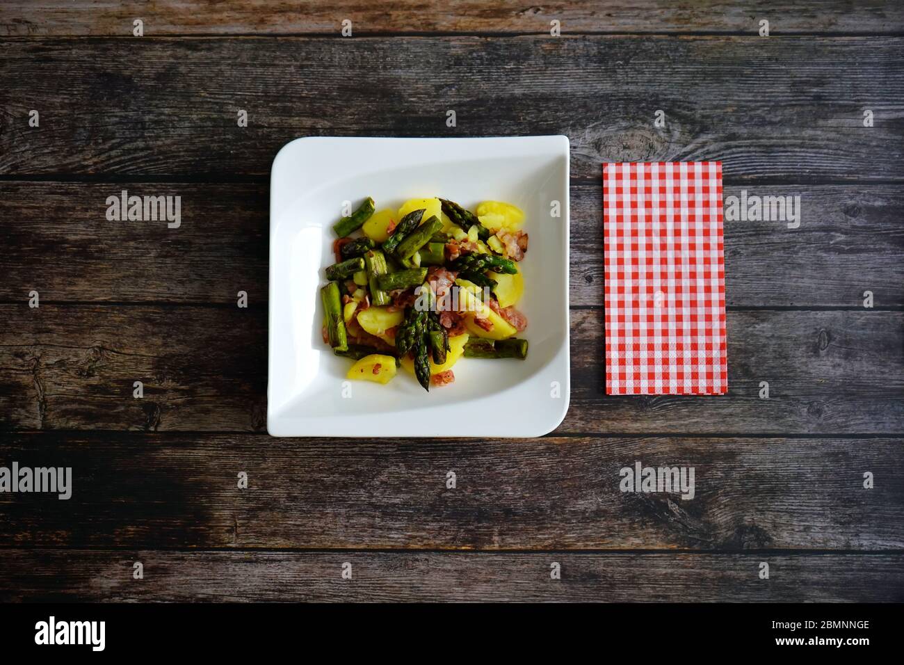 Gebratener grüner Spargel und warmer Kartoffelsalat mit Speck und Zwiebeln. Gesunde Hausmannskost. Kartoffelsalat ist ein beliebtes und traditionelles deutsches Gericht. Stockfoto