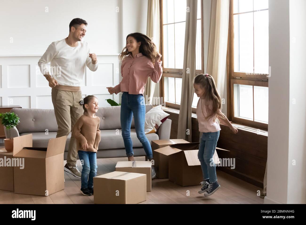 Glückliche Familie mit zwei Töchtern, die den Umzugstag feiern Stockfoto