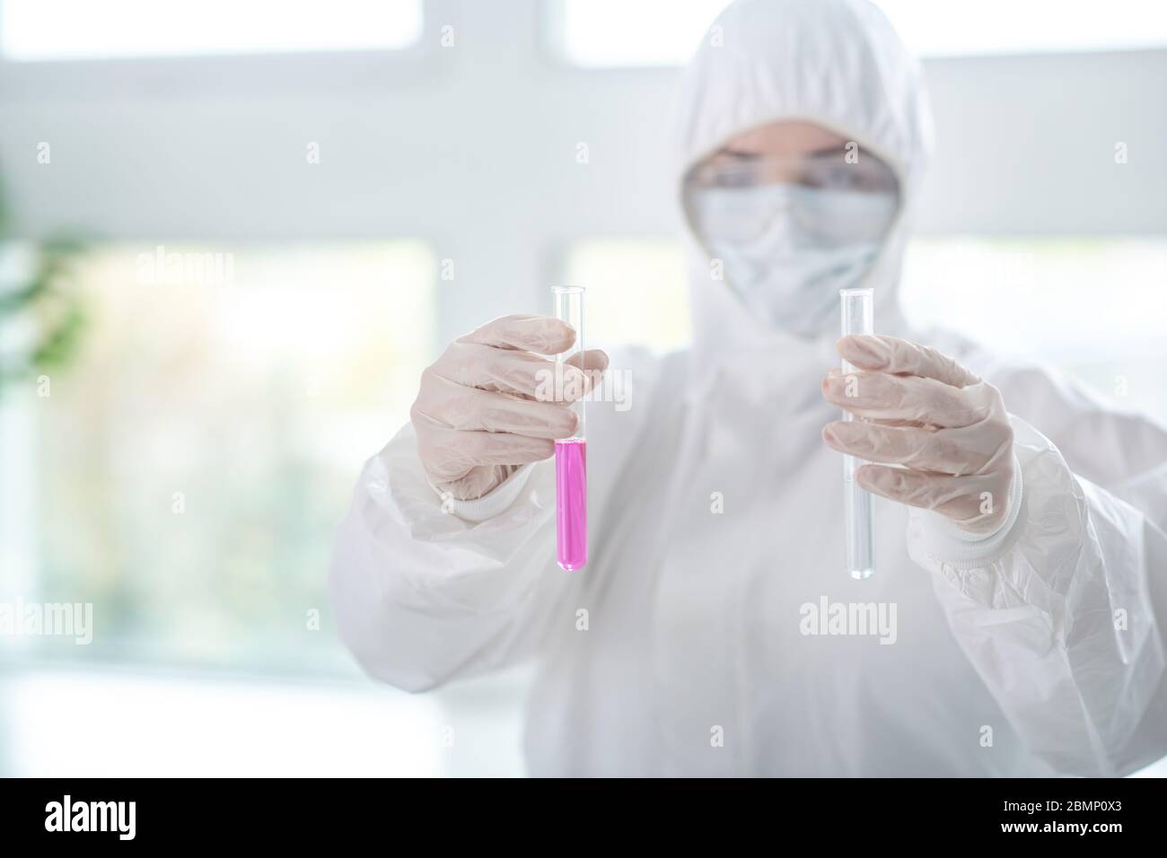 Desinfizieren von Arbeitskleidung, die die Reagenzgläser hält Stockfoto