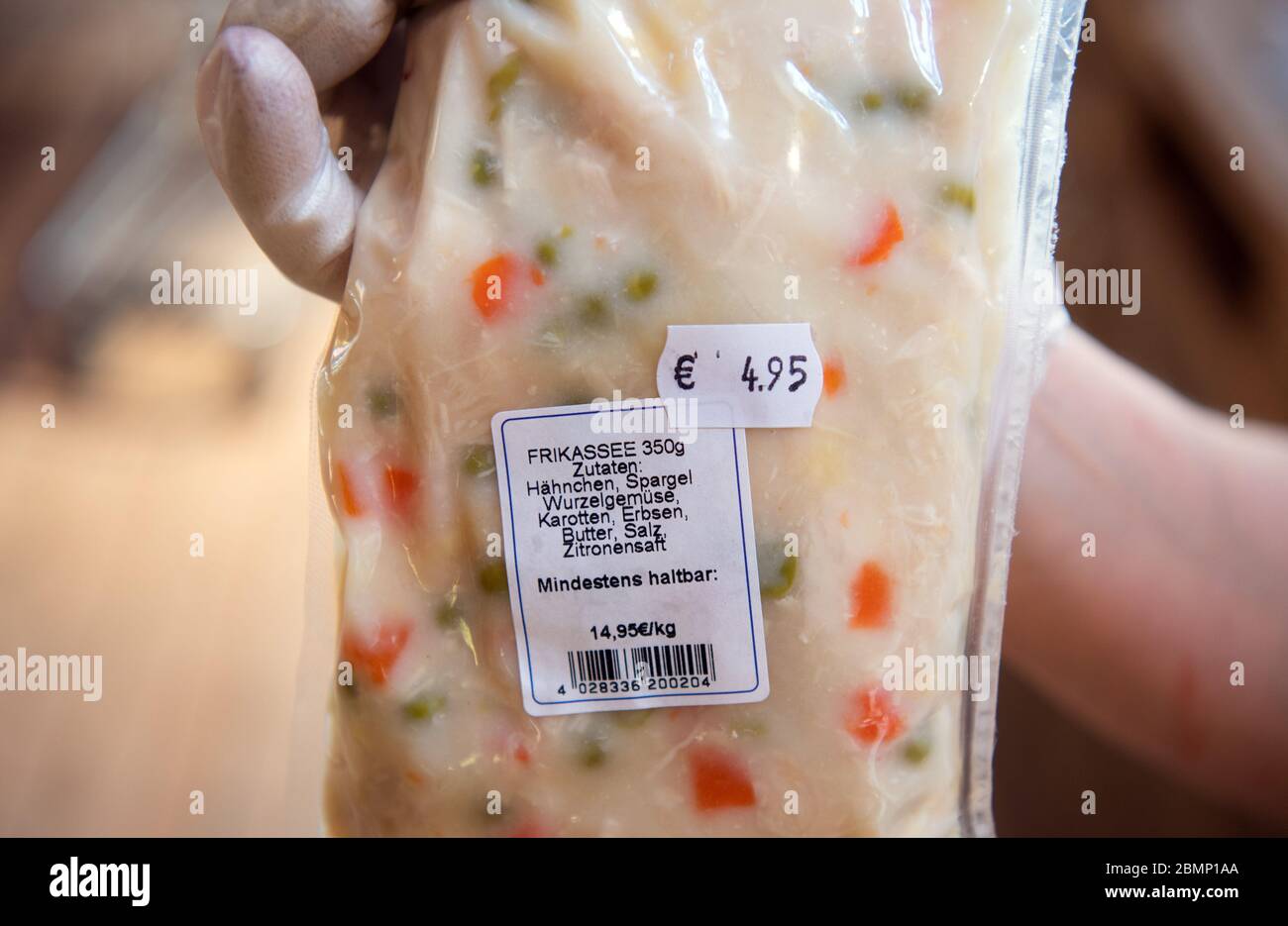 21. April 2020, Brandenburg, Klaistow: Im Hofladen zeigt Verkäuferin Iwona ein Päckchen Hühnerfricassee, das nach Sous-vide-Methode vorgekocht wird. Die vorgekochten Speisen sind verfügbar, da das Restaurant wegen der Corona-Pandemie geschlossen werden musste. Die Beutel mit Hühnerfricassee, Kohlbrötchen und Spargel müssen zu Hause nur etwa zehn Minuten im warmen Wasserbad erwärmt werden und sind verzehrfertig. Die Spargel- und Erlebnisfarm Klaistow ist ein Familienunternehmen. 1991 ließen Gärtnermeister Jörg Buschmann und Unternehmer Ernst-August Winkelmann die Tradition des Spargelanbaus wieder aufleben Stockfoto