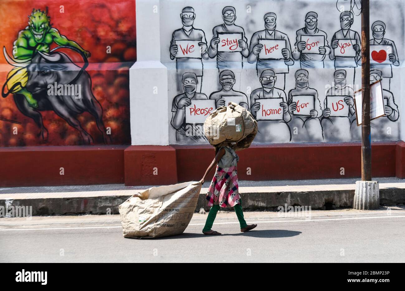 Guwahati, Assam, Indien. Mai 2020. Ein Mädchen trägt Müll, als sie während der andauernden Sperrung von COVID-19 zu einem Wandbild vorbeigeht. Kredit: David Talukdar/ZUMA Wire/Alamy Live News Stockfoto