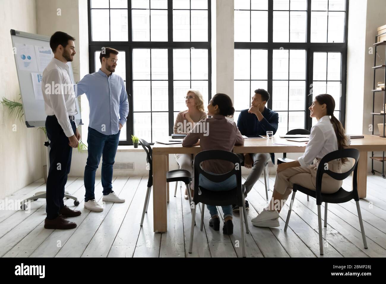 Geschäftsmann im Namen des Unternehmens begrüßen junge männliche Mitarbeiter. Stockfoto