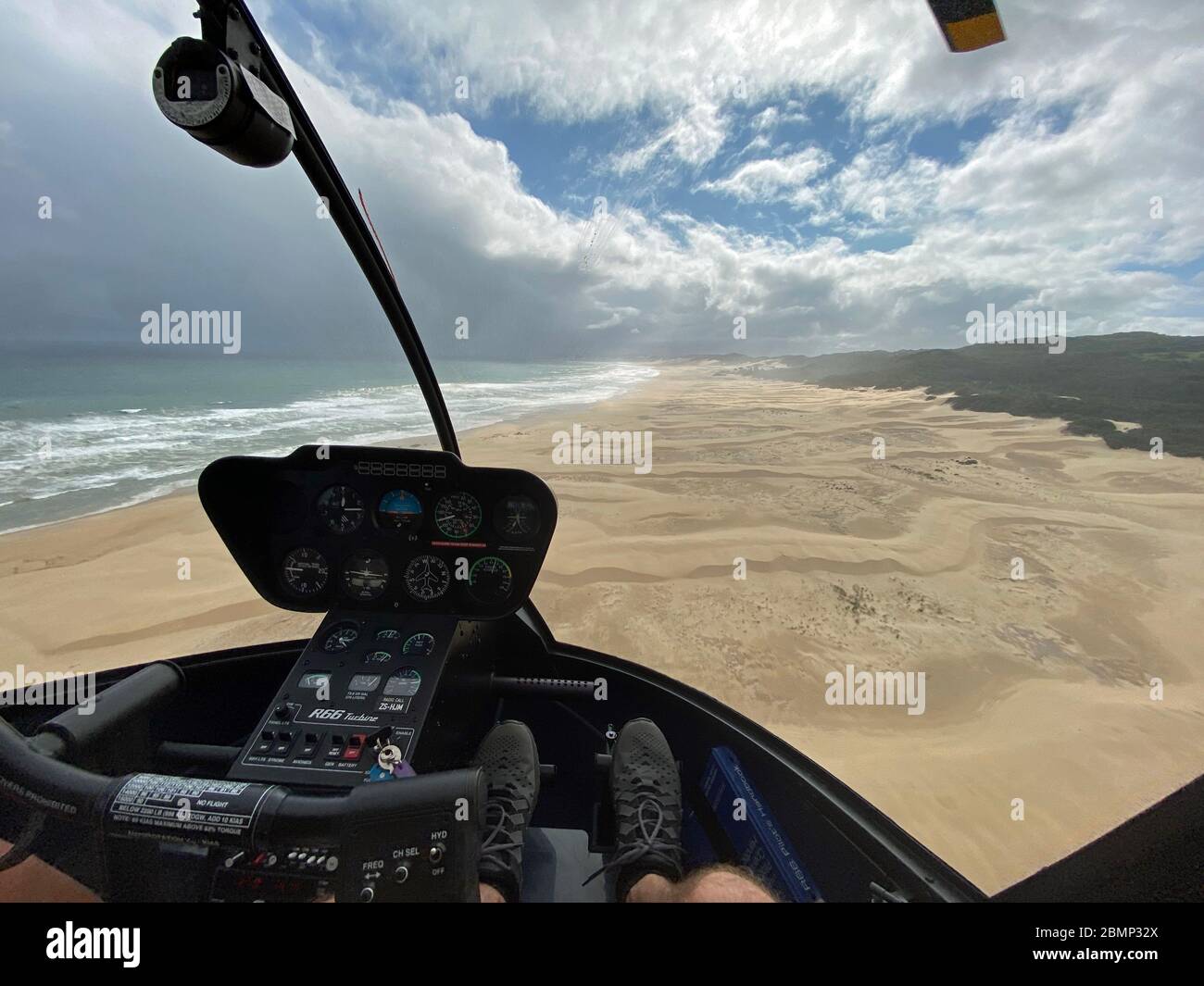 Diese Helikopterpiloten haben einen einzigartigen Blick aus ihrem Cockpit neben den Instrumenten während sie über den Strand entlang der Küstenlinie fliegen. Stockfoto