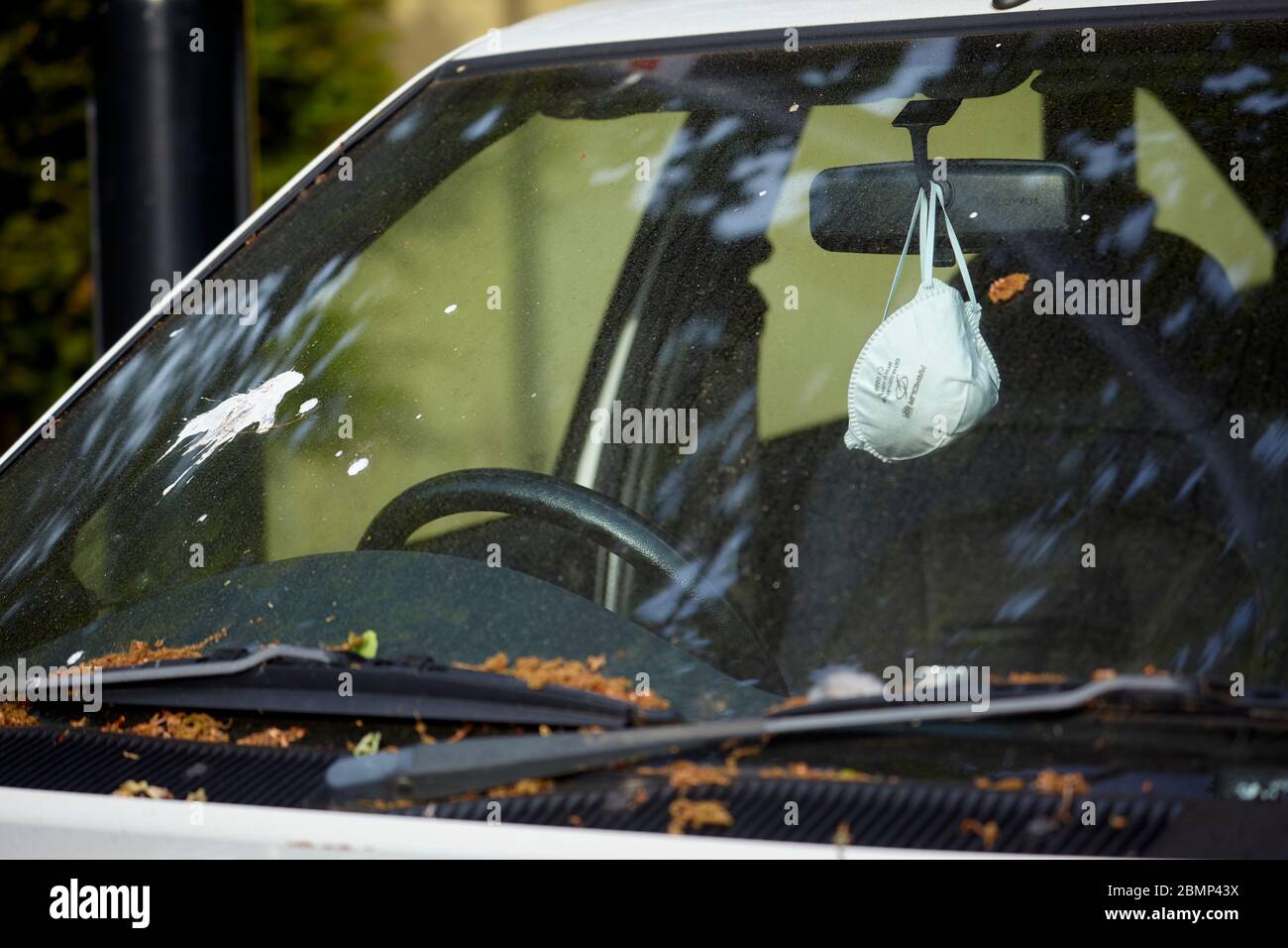 Die Facemask hängt einen Rückspiegel im geparkten Auto während des Covid-19 Ausbruchs, Frühjahr 2020, London Stockfoto