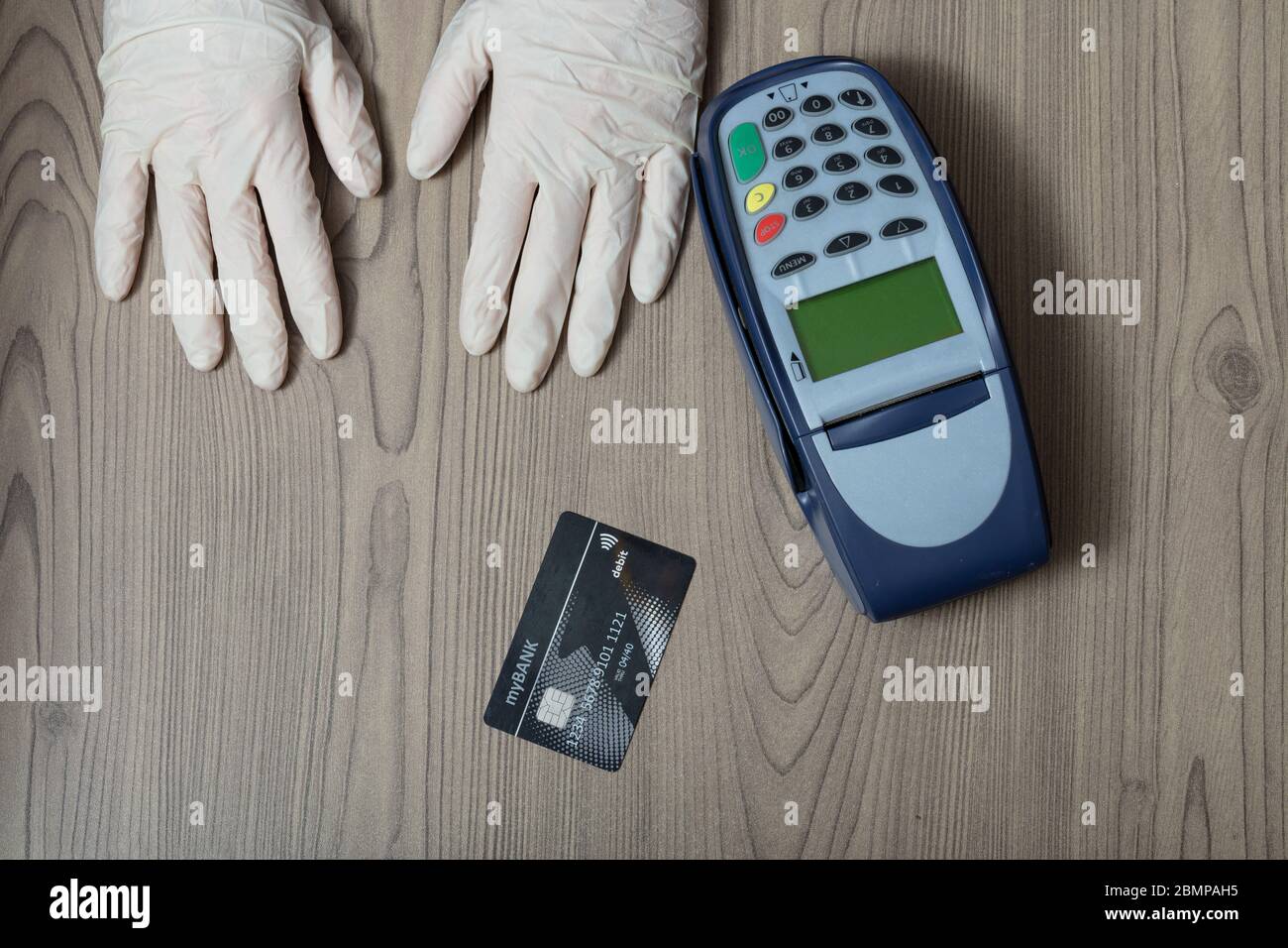 Handschuhesten neben einer Bankkarte und einem Gerät, das bereit ist, während der Covid-19-Pandemie für einen Ladenkauf zu bezahlen Stockfoto