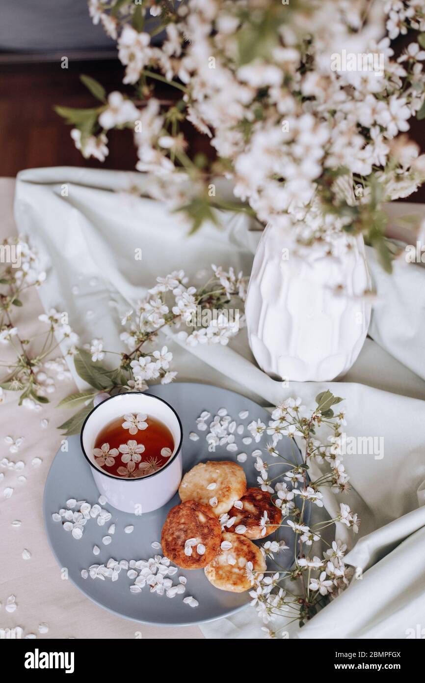 Frühstück am Morgen, getoastete schöne Käsekuchen auf einem Teller auf der Tischdecke neben einem Frühlingsstrauß aus weißen Blumen Stockfoto