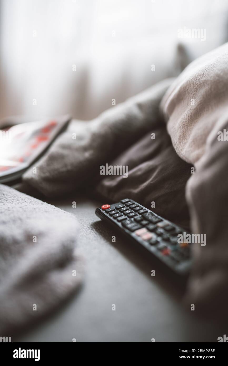 Eine Fernbedienung liegt auf einem Sofa zwischen Kissen Stockfoto