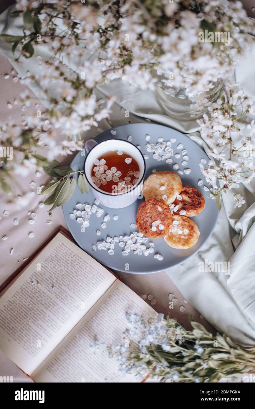 Frühstück am Morgen, getoastete schöne Käsekuchen auf einem Teller auf der Tischdecke neben einem Frühlingsstrauß aus weißen Blumen Stockfoto