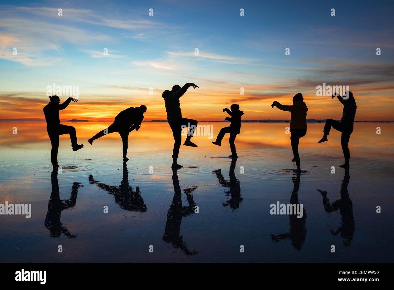 Lustige Aufnahme junger Reisender in Uyuni Salt Flats (spanisch: Salar de Uyuni ) bei Sonnenaufgang in Bolivien, Südamerika. Stockfoto