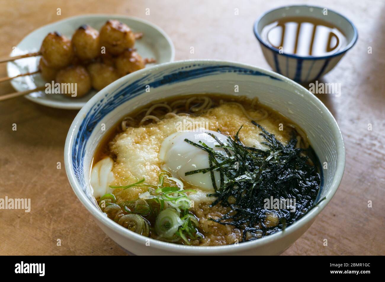 Japanische Soba-Rament-Suppe mit Ei und Algen und gegrillte Knödel mit grünem Tee auf der Seite. Traditionelle japanische Speisesuppe Stockfoto