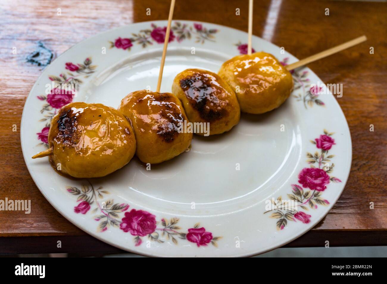 Japanische Dango süße Knödel auf rustikalem Teller. Traditionelle japanische Reismehl Mochi wie Dessert auf Spieß mit süßer Sauce gegrillt Stockfoto