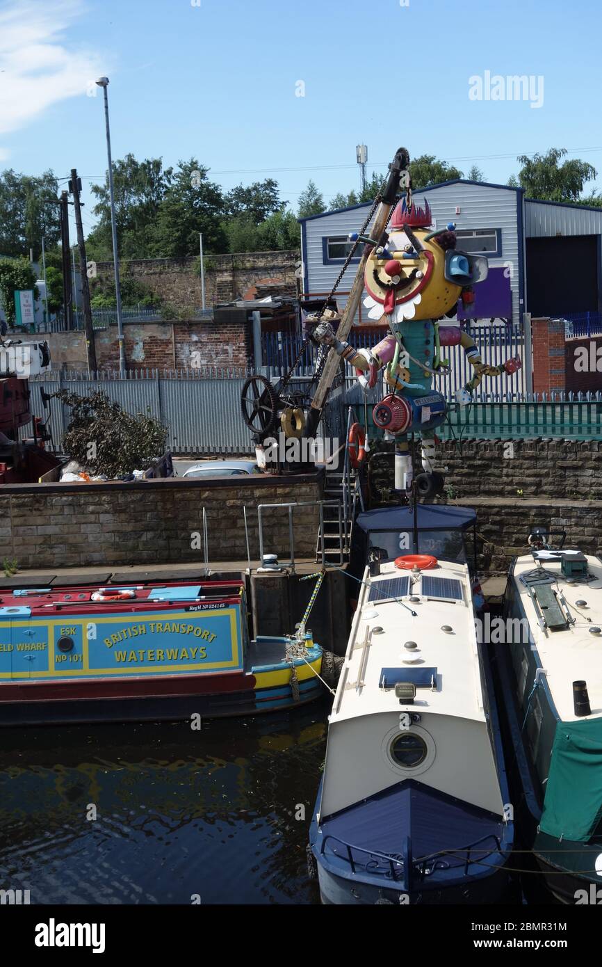 Clownskulptur aus Schrott neben einer Bootswerft am Ufer der Calder, gegenüber dem Eingang zur Hepworth Gallery. Stockfoto
