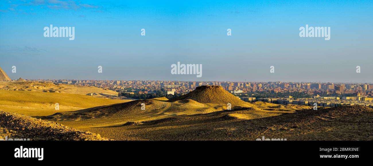 Wüstenlandschaft auf dem Gizeh Plateau mit Kairo Skyline im Hintergrund Stockfoto