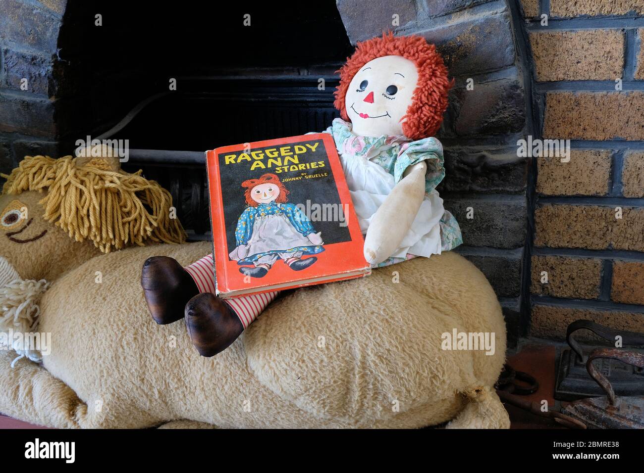 Raggedy Ann Puppe sitzt an einem Kamin mit einem Nachdruck von 1961 des  Buches Raggedy Ann Stories von Johnny Gruel auf dem Schoß; RAG Puppe  Stockfotografie - Alamy