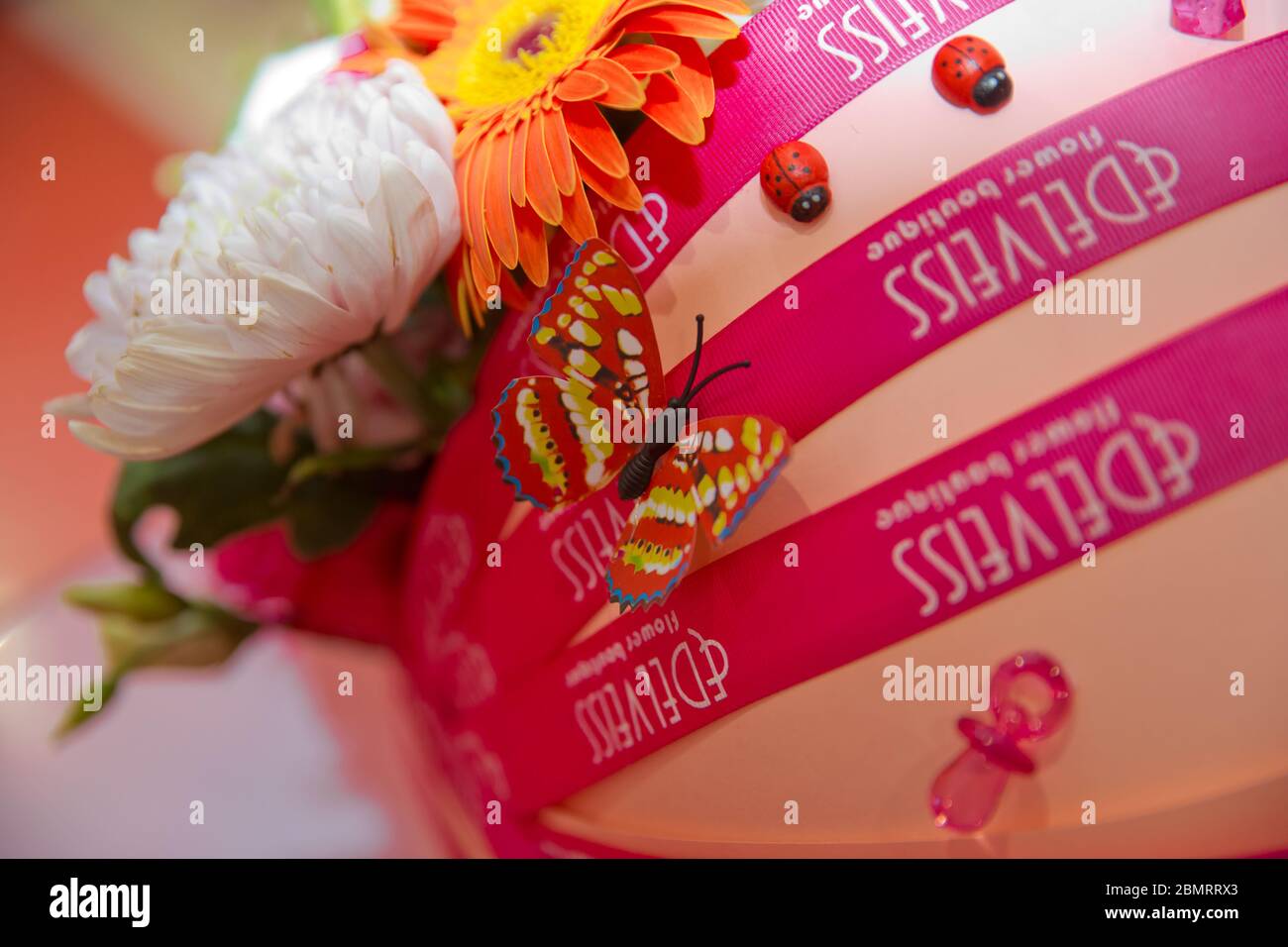 Blumenstrauß für die Geburt eines Kindes. Wagen Bouquet . Bunte Blumen . Gelbe und rote künstliche Schmetterlinge . Stockfoto