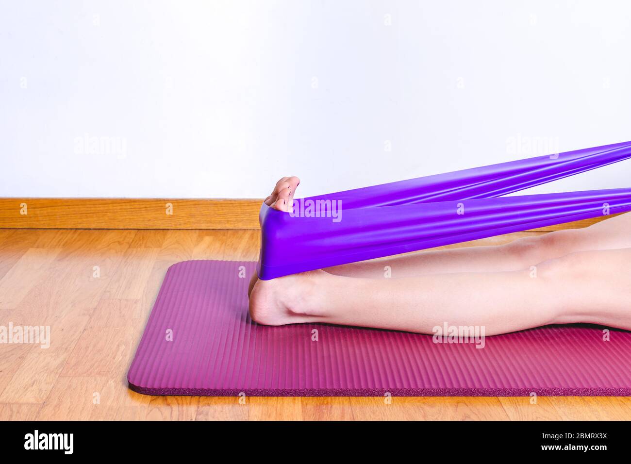 Detail der kaukasischen Frau Stretching Kälber mit einem lila Turnhalle elastisches Band Stockfoto