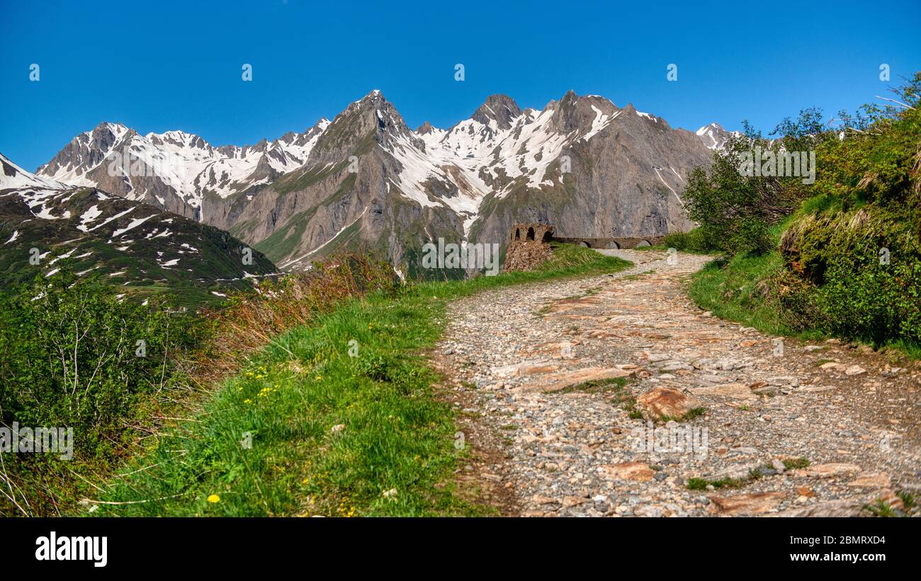 Bergpfad mit schneebedecktem Gipfel im Hintergrund, Formazza Tal im Sommer Stockfoto