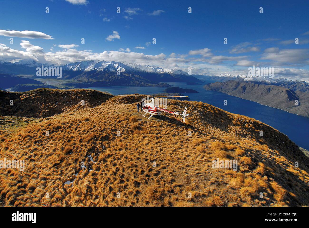 Robinson R44 Hubschrauber über dann südlichen Seen von Neuseeland, mit schneebedeckten alpinen Bereich hinter. Stockfoto