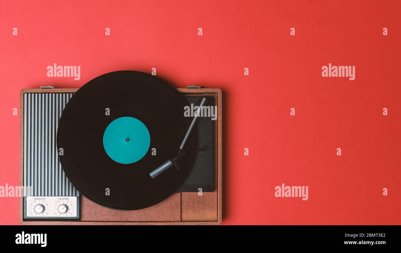 Vinyl-Vinyl-Player und drehbar auf rotem Hintergrund. Unterhaltung 70er Jahre. Hören Sie Musik. Draufsicht. Stockfoto