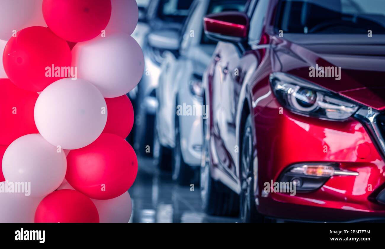 Rote und weiße Ballons in modernen Autohaus auf verschwommenen Vorderansicht roten SUV Auto dekoriert. Neue und glänzende Luxus-SUV-Auto in modernen Showroom geparkt. Stockfoto