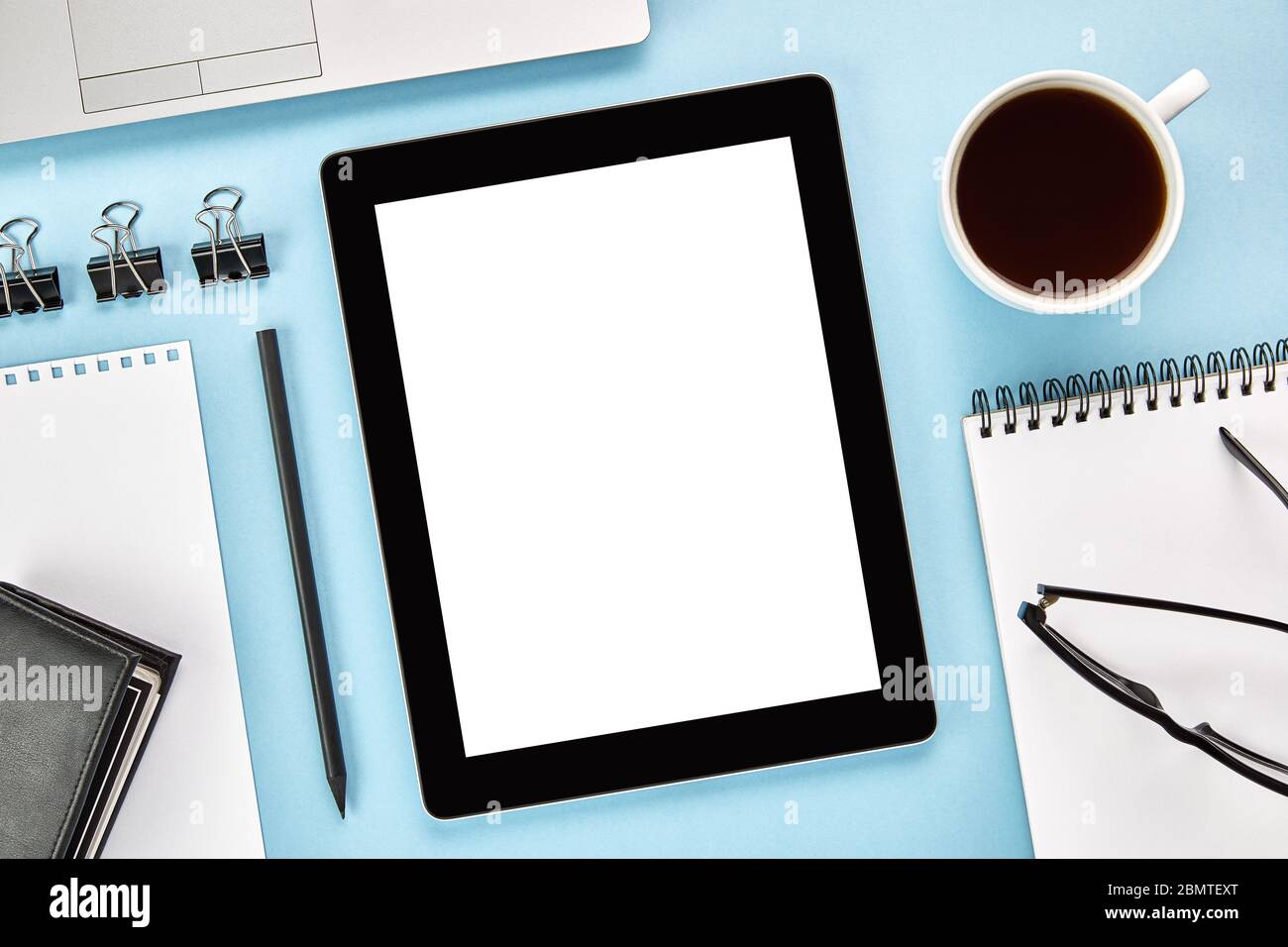 Mockup-Bild eines vertikalen Tablet-Computers mit leerem weißen Bildschirm auf blauer Oberfläche. Flaches Lay Stockfoto