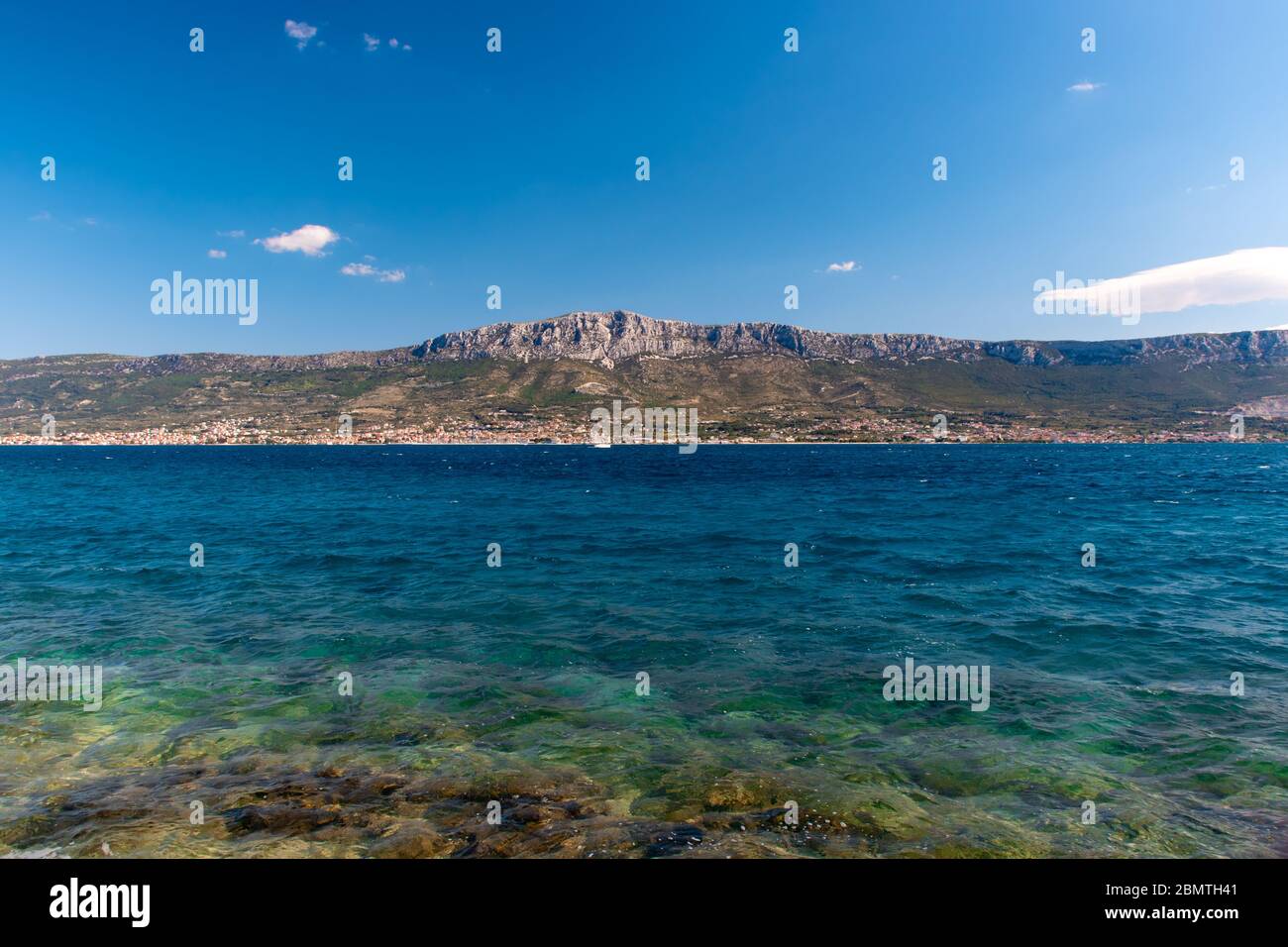 Mehrere Städte in der Ferne, Teil der Gruppe der Städte 'Kastela'. Von weit weg von Split gesehen. Helle schöne sonnige Tag, Yacht in der offenen adria Stockfoto