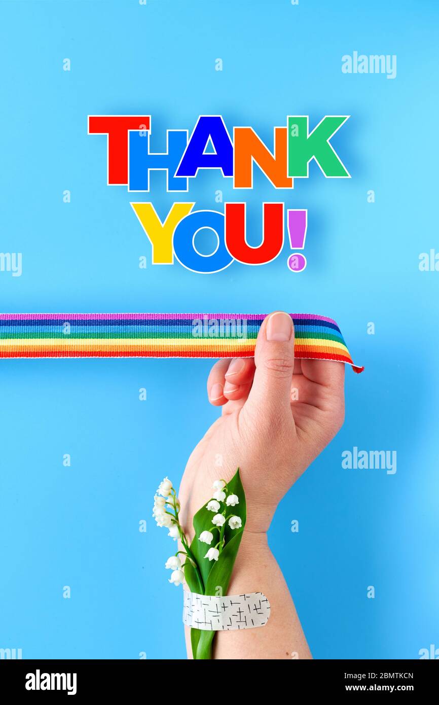 Regenbogen Band in der Hand der Frau. Kamille Blumen und Gras Bouquet am Handgelenk mit medizinischen Patch befestigt. Danke, Ärzte und Krankenschwestern. Kreative Wohnung Stockfoto