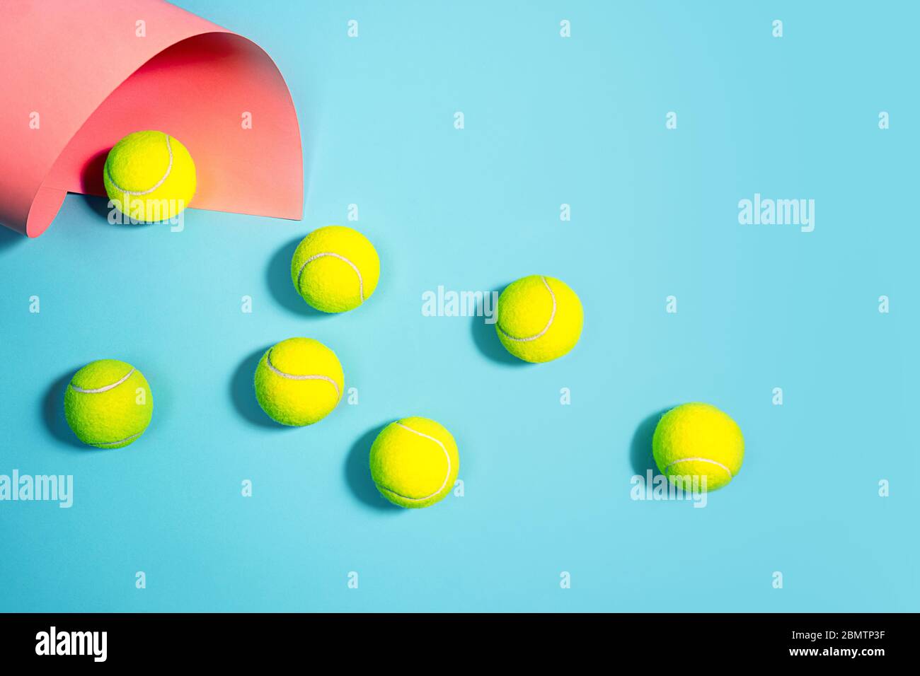 Sportkonzept mit Tennisbällen aus nächster Nähe auf blauem Tennisplatz. Kopierbereich, selektiver Fokus. Blau, rosa und gelb. Stockfoto